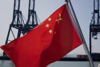 1767805492242-sebuah-bendera-china-yang-sedang-berkibar-di-depan-mesin-pengangkut-kargo-di-pelabuhan-di-china_43